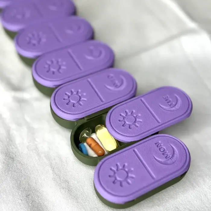 urple pill organizer with open compartments displaying pills and supplements inside, designed for daily medication management.