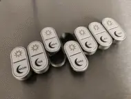 Black and white 3D-printed pill organizers with engraved sun and moon symbols, offering a stylish alternative color option